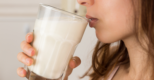 woman drinking a full glass of milk